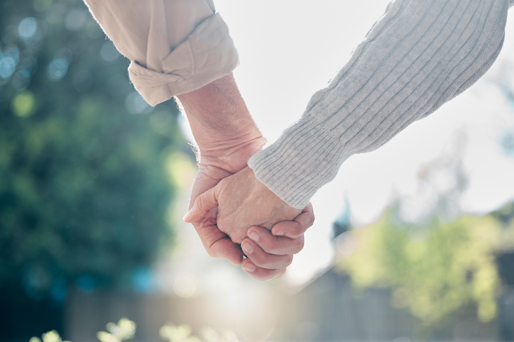 People holding hands in a garden.